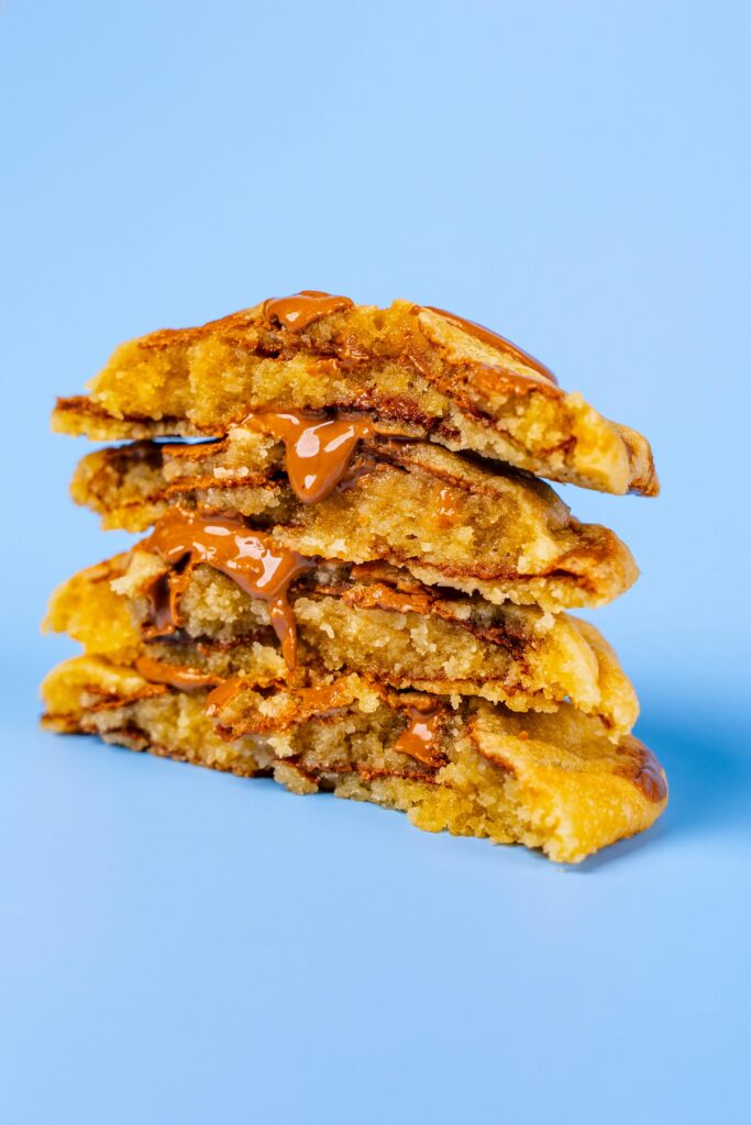 Delicious stack of chocolate-filled cookies oozing with melted cream, set against a pastel blue backdrop.