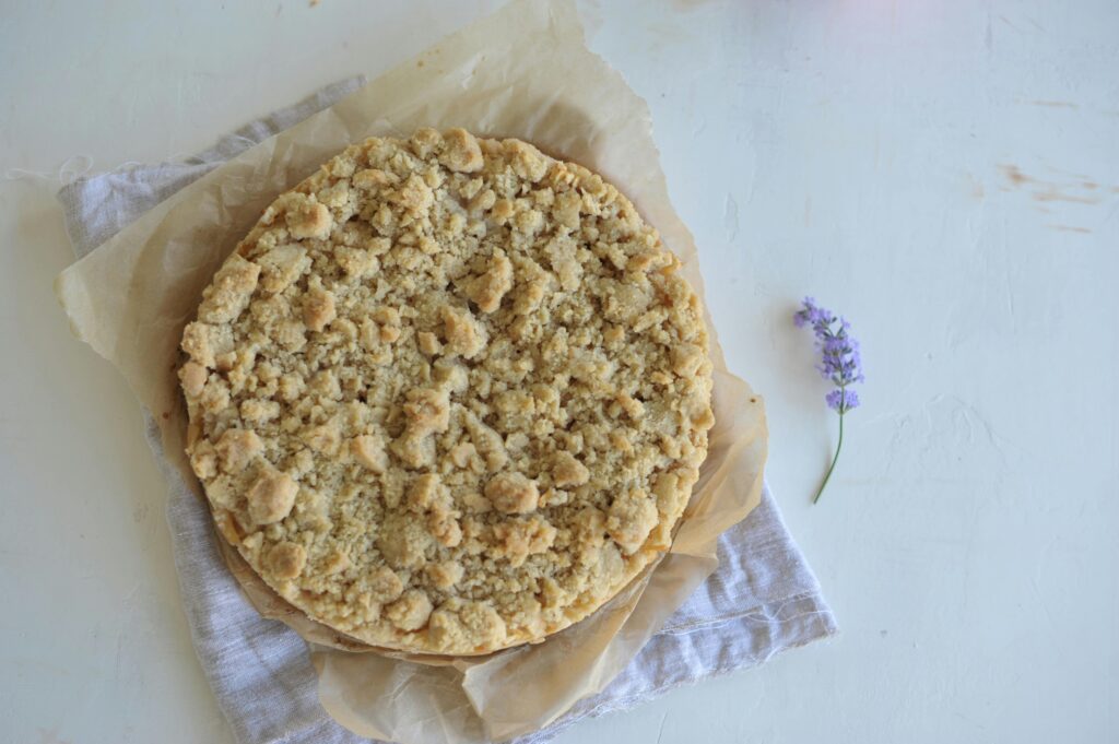 Rustic crumb cake on paper with a lavender flower, perfect for cozy settings.