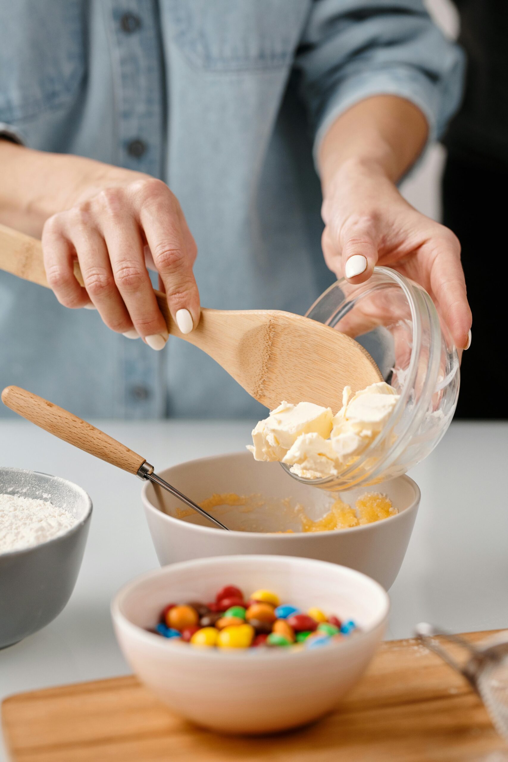Forever Baked Close-up of hands adding butter for baking with colorful candies nearby.